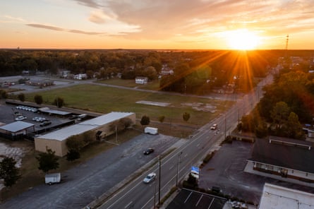 And aerial picture of an office building next to a road with the sun at the horizon.