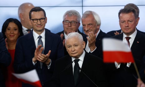 Poland’s deputy prime minister and the leader of the Law and Justice party (PiS), Jarosław Kaczyński (centre), stands next to the Polish prime minister, Mateusz Morawiecki, also of PiS, as he addresses supporters at the party’s headquarters in Warsaw on 15 October after the first exit poll results for parliamentary elections.